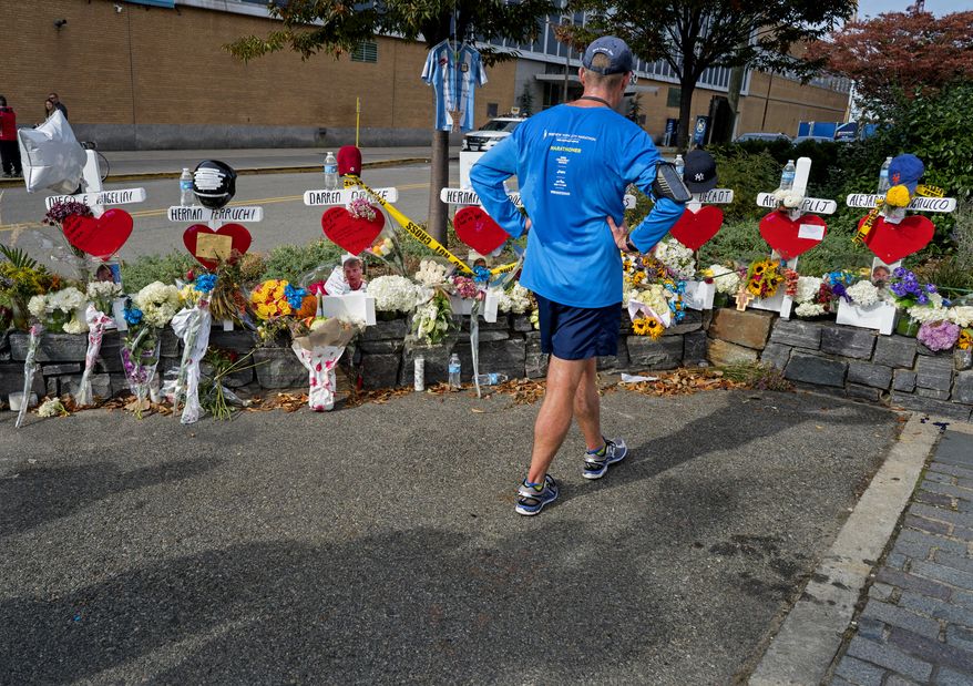 CORRECTS TO HOUSTON NOT CHAMBERS STREET A passerby pauses at a makeshift memorial near a bike path that honors victims of an attack who were stuck and killed by a rental truck driven by indicted suspect Sayfullo Saipov last Tuesday, at Houston and West Streets in New York, Saturday, Nov. 4, 2017. Saipov is accused of using the rental truck to mow down pedestrians and cyclists along the busy bike path. (AP Photo/Craig Ruttle)