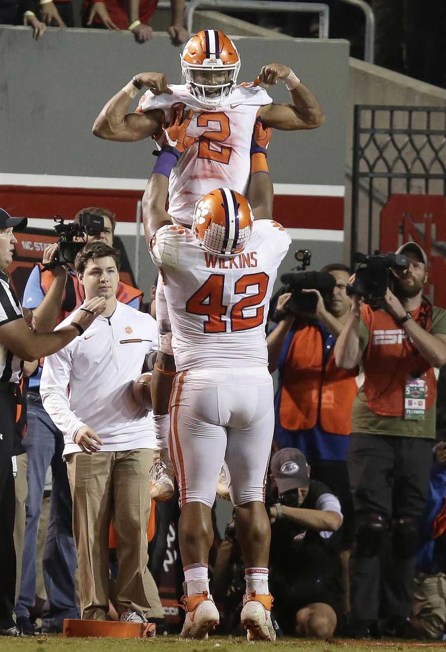 Clemson's Christian Wilkins (42) lifts quarterback Kelly Bryant (2) following Bryant's touchdown against North Carolina State during the second half of an NCAA college football game in Raleigh, N.C., Saturday, Nov. 4, 2017. Clemson won 38-31. (AP Photo/Gerry Broome)