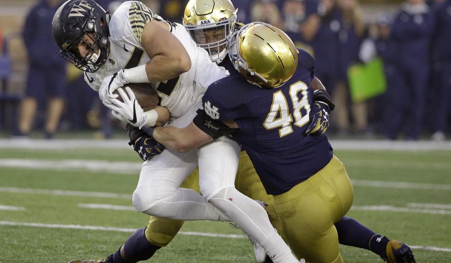 Wake Forest tight end Cam Serigne, left, is tackled by Notre Dame linebacker Nyles Morgan and linebacker Greer Martini (48) during the second half of an NCAA college football game Saturday, Nov. 4, 2017, in South Bend, Ind. (AP Photo/Nam Y. Huh)