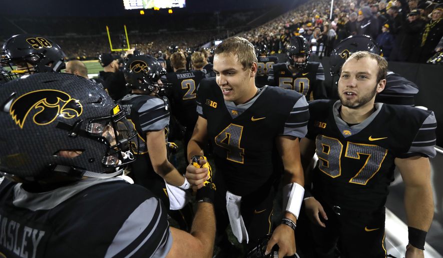 Iowa quarterback Nathan Stanley (4) and Tyler Kluver, right, celebrate with teammate Nick Easley, left, after an NCAA college football game against Ohio State, Saturday, Nov. 4, 2017, in Iowa City, Iowa. (AP Photo/Charlie Neibergall)