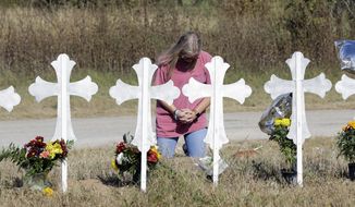 A woman kneels in prayer at a makeshift memorial for the First Baptist Church shooting victims Tuesday, Nov. 7, 2017, in Sutherland Springs, Texas. A man opened fire inside the church in the small South Texas community on Sunday, killing more than two dozen and injuring others. (AP Photo/David J. Phillip)