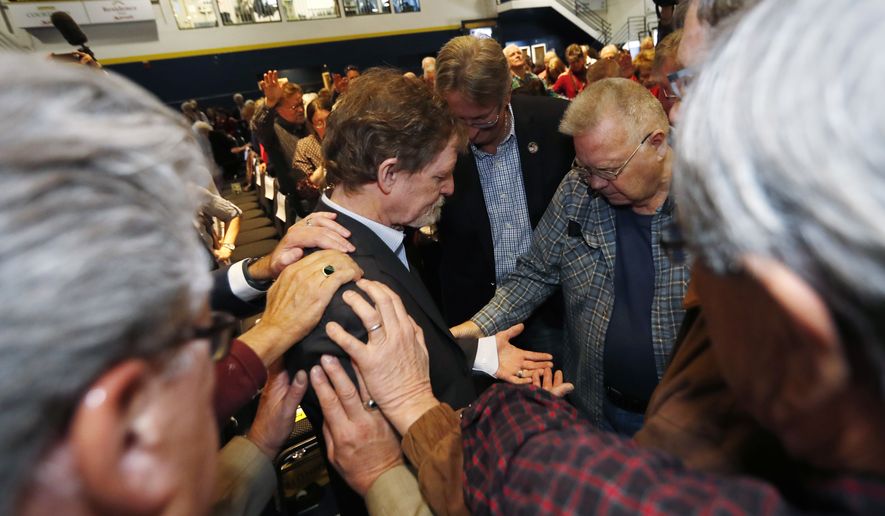 Jack Phillips, owner of Masterpiece Cake, center, is surrounded and prayed for by supporters after a rally on the campus of a Christian college Wednesday, Nov. 8, 2017, in Lakewood, Colo. The small rally was held to build support for Phillips, who is at the center of a case that will be considered by the U.S. Supreme Court in December. The case may determine if business owners like Phillips are having their right of religious liberty and free expression violated by having to offer their wedding services to same-sex couples. (AP Photo/David Zalubowski)