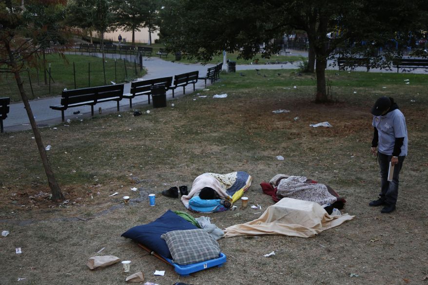 In this Wednesday, Oct. 4, 2017, photo, Center for Urban Community Services caseworker Gladys Rivera talks to some homeless people sleeping in a park in the Harlem section of New York. Rivera is part of a citywide, round-the-clock army of workers for nonprofits contracted by the city. Their aim is to get the homeless into shelter, and so they make the rounds of upper Manhattan, checking on clients, identifying newcomers to the streets and trying to connect them with services. They are often rejected, but they do not give up. (AP Photo/Seth Wenig)