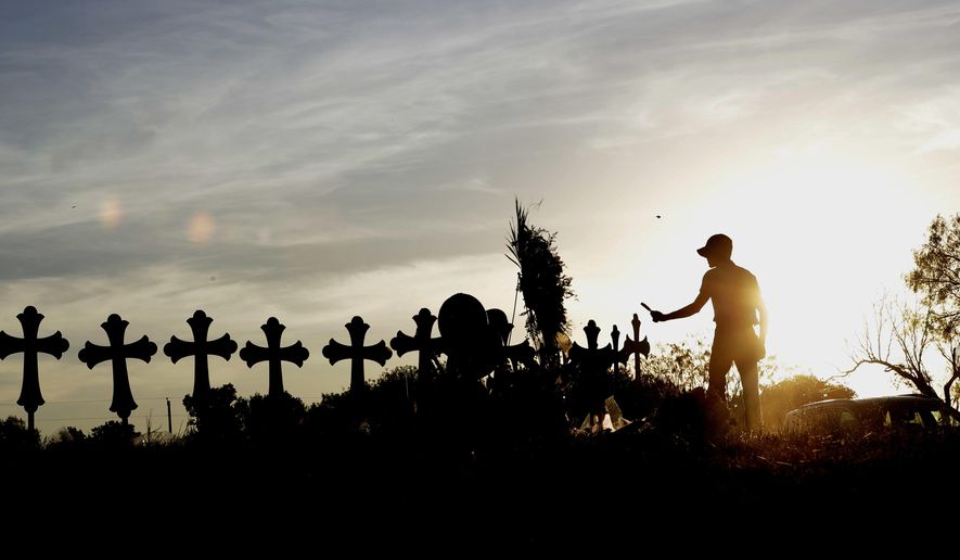 Derrick Bernoden burns sage at a makshift memorial for the First Baptist Church victims Tuesday, Nov. 7, 2017, in Sutherland Springs, Texas. A man opened fire inside the church in the small South Texas community on Sunday, killing more than two dozen and injuring others. (AP Photo/David J. Phillip)
