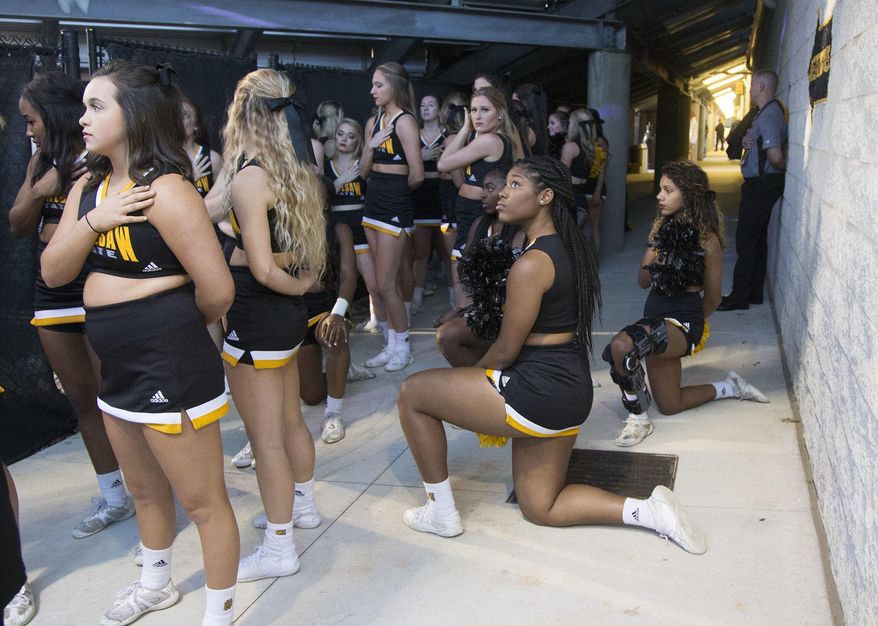 In this Saturday, Oct. 21, 2017, file photo, Four of the five Kennesaw State cheerleaders who took a knee three weeks ago during the Kennesaw State football game, take a knee once again out of sight of the fans under the visitors' bleachers, during the national anthem before an NCAA college football game between Kennesaw State and Gardner-Webb in Kennesaw, Ga. Kennesaw State, which moved its football cheerleaders inside a stadium tunnel after a group of black cheer squad members knelt during the national anthem, has decided to let them again take the field during pre-game ceremonies. (Kelly J. Huff/The Marietta Daily Journal via AP, File)