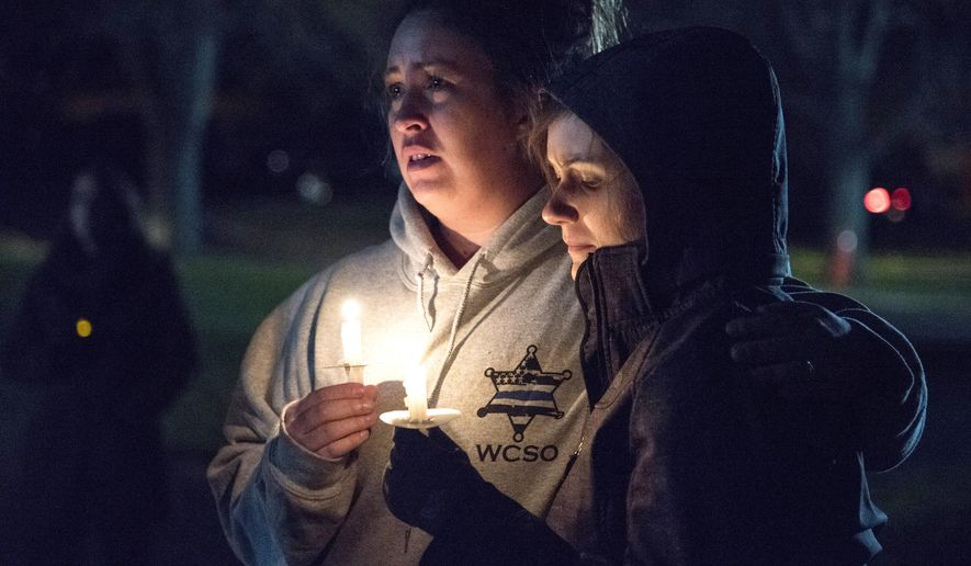 In this Nov. 6, 2017 photo community members listen to prayers read at a vigil in honor of fallen Rockford police officer Jaimie Cox in Rockford, Ill. Cox died during a traffic stop Sunday, Nov. 5, 2017 in Rockford, Ill. Authorities say Cox and another man were both found dead at the scene of a single-vehicle crash. Rockford police Chief Dan O'Shea says Cox became "entangled" with the car and fired a shot, but he declined to say how either man died or to provide additional details. (Kayli Plotner/Rockford Register Star via AP)