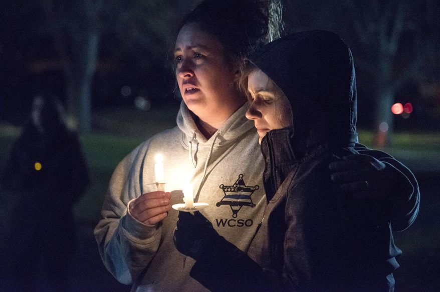 In this Nov. 6, 2017 photo community members listen to prayers read at a vigil in honor of fallen Rockford police officer Jaimie Cox in Rockford, Ill. Cox died during a traffic stop Sunday, Nov. 5, 2017 in Rockford, Ill. Authorities say Cox and another man were both found dead at the scene of a single-vehicle crash. Rockford police Chief Dan O'Shea says Cox became "entangled" with the car and fired a shot, but he declined to say how either man died or to provide additional details. (Kayli Plotner/Rockford Register Star via AP)