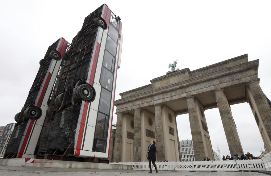 Three busses are positioned close to the 'Brandeburg Gate' in Berlin, Germany, Friday, Nov. 10, 2017. Syrian artist Manaf Halbouni placed the three buses upright in the German capital, to remind on the suffering of civilians in the Syrian city of Aleppo. (AP Photo/Michael Sohn)