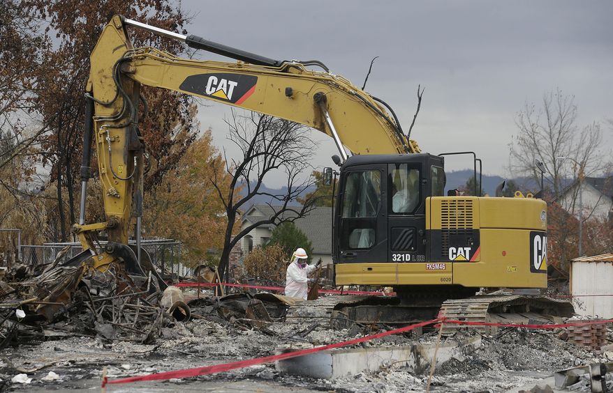 Work crews remove debris a the site of a home destroyed by fires in the Coffey Park area of Santa Rosa, Calif., Wednesday, Nov. 8, 2017. Rumbling front loaders began scraping up the ash and rubble of nearly 9,000 destroyed homes and other structures in Northern California this week as the U.S. Army Corps of Engineers launched a new phase of the largest wildfire clean-up in the state's history. (AP Photo/Jeff Chiu)