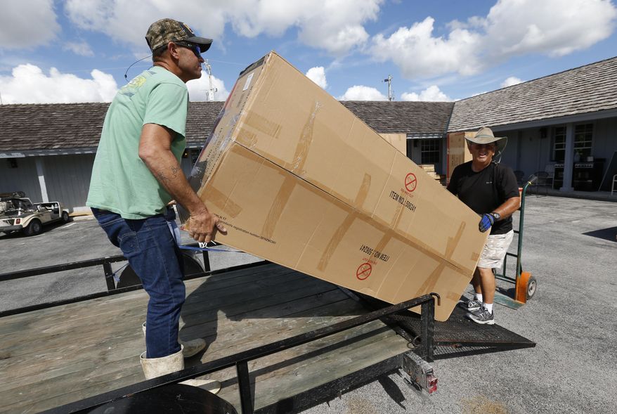 In this Thursday, Nov. 9, 2017 photo, volunteer Danny Floyd, right, of Weatherford, Okla,, helps Kenny and Brittany Smallwood, left, load new furniture donated by the nation's Churches of Christ, at Outdoor Resorts of Chokoloskee, in Chokoloskee, Fla. Kenny and Brittany Smallwood say FEMA rejected their assistance request after an 8-minute inspection even though Hurricane Irma's torrential rains poured through the hole it tore in their home's roof, destroying much of their furniture and causing extensive damage. They say they were denied financial aid because one room remains livable. They share it with their three young sons. (AP Photo/Wilfredo Lee)