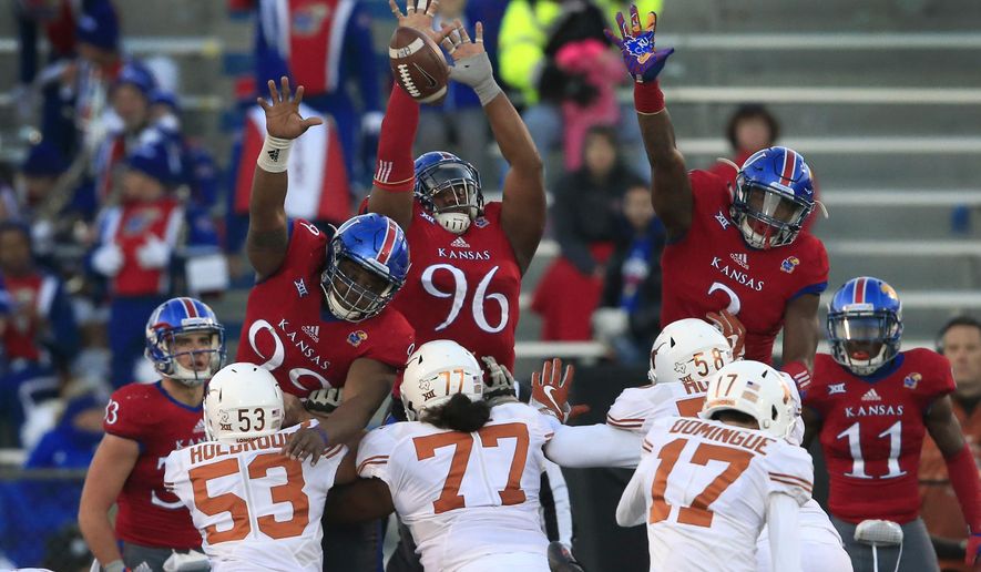 FILE - In this Nov. 19, 2016, file photo, Texas place kicker Trent Domingue (17) kicks a point after touchdown over Kansas defensive tackles Daniel Wise (96), DeeIsaac Davis (99) and defensive end Dorance Armstrong Jr. (2) during the second half of an NCAA college football game in Lawrence, Kan. The Jayhawks head to Texas this week looking for a repeat of their shocking win in 2016. (AP Photo/Orlin Wagner, File)