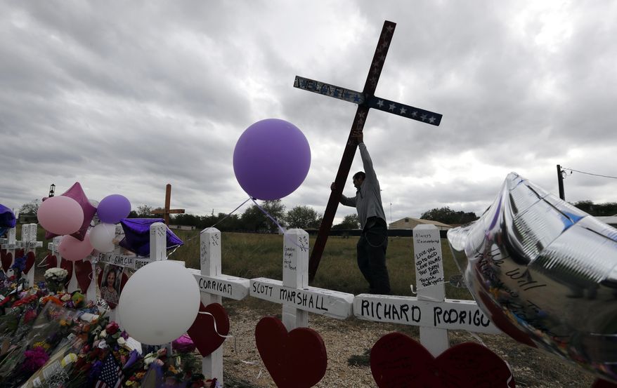 Miguel Zamora stands a cross for the victims of the Sutherland Springs First Baptist Church shooting at a makeshift memorial, Saturday, Nov. 11, 2017, in Sutherland Springs, Texas. A man opened fire inside the church in the small South Texas community on Sunday, killing more than two dozen. Zamora carried the cross for three days to reach the site. (AP Photo/Eric Gay)
