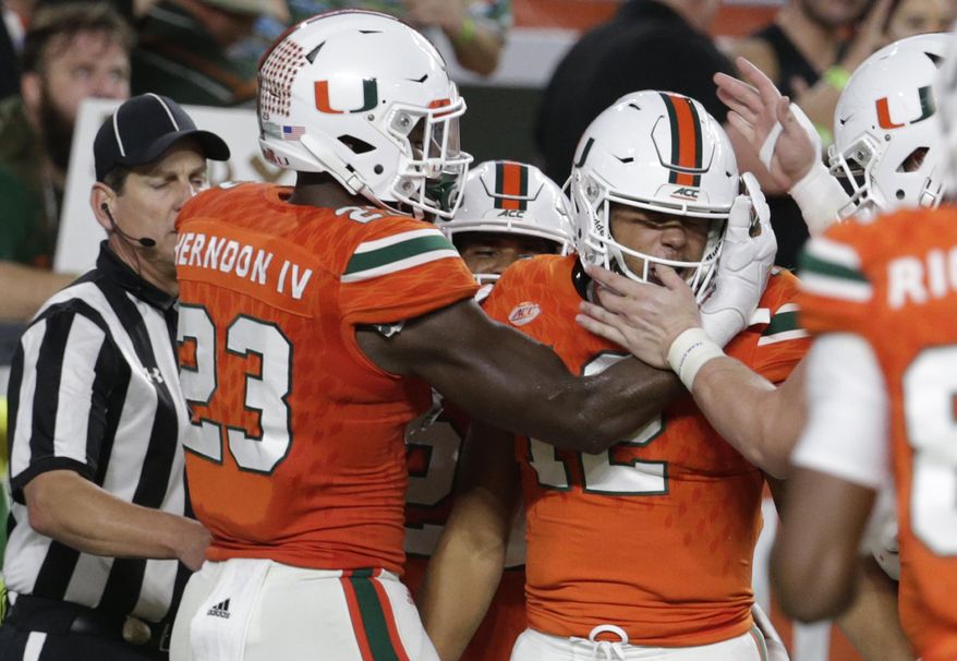 Miami quarterback Malik Rosier (12) is congratulated by Christopher Herndon IV (23) after running for a touchdown during the first half of an NCAA college football game against Notre Dame, Saturday, Nov. 11, 2017, in Miami Gardens, Fla. (AP Photo/Lynne Sladky)