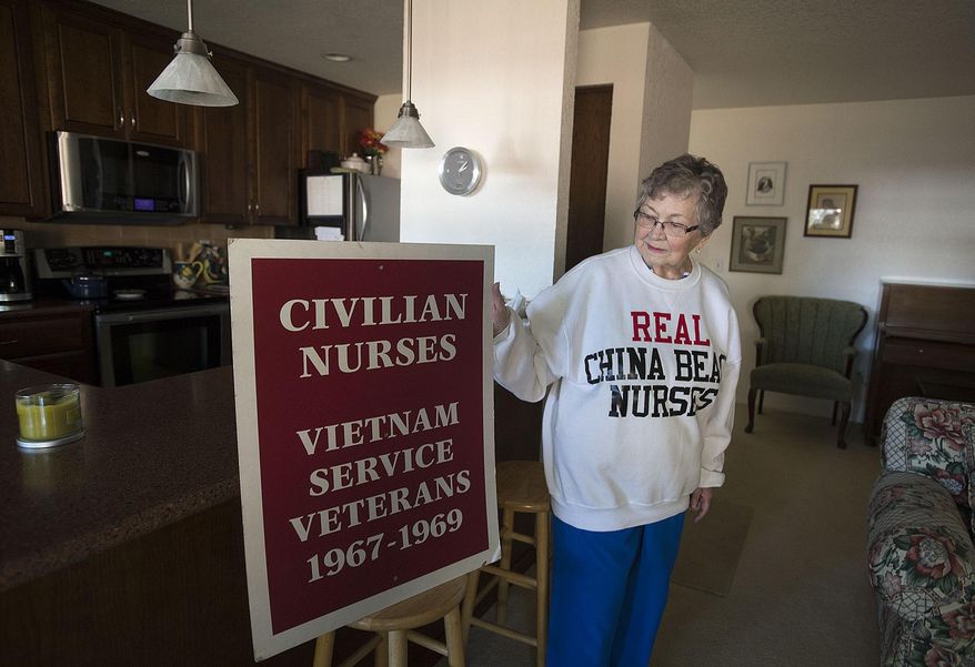 Vietnam War nurse Marion Mullin poses at her Vancouver home on Thursday, Sept. 28, 2017, with the sweatshirt and the sign she carried during the 1993 dedication of the Women's Vietnam War Memorial in Washington D.C. Mullin was a civilian nurse in Danang during the Tet offensive. (Amanda Cowan/The Columbian via AP)