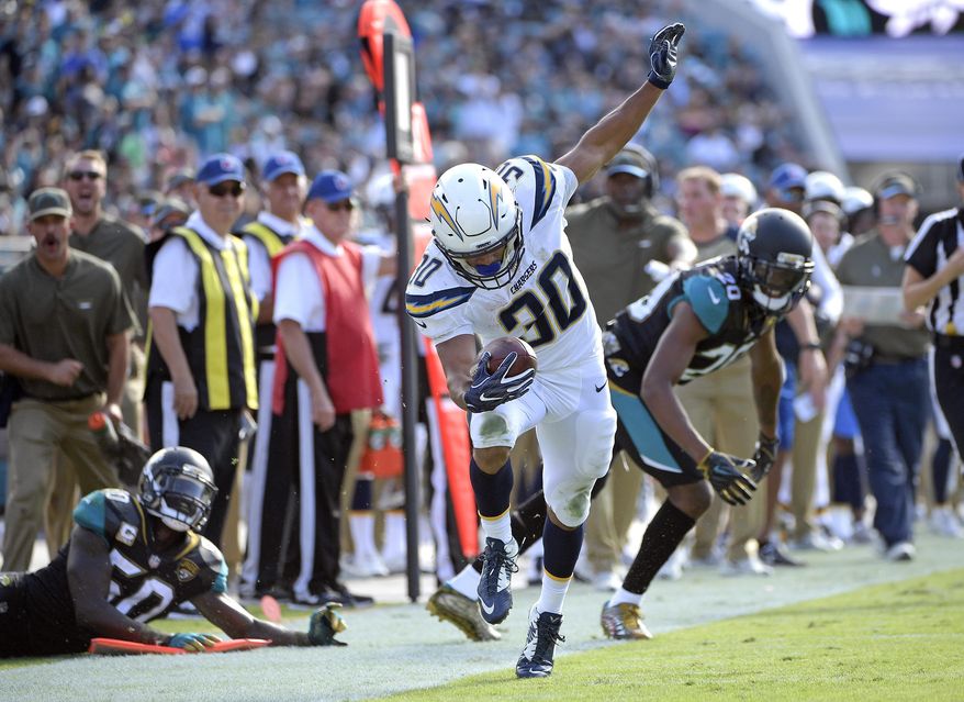 Los Angeles Chargers running back Austin Ekeler (30) tries to stay in bounds as he runs past Jacksonville Jaguars linebacker Telvin Smith, left, and cornerback Jalen Ramsey, right, during the first half of an NFL football game, Sunday, Nov. 12, 2017, in Jacksonville, Fla. (AP Photo/Phelan M. Ebenhack)