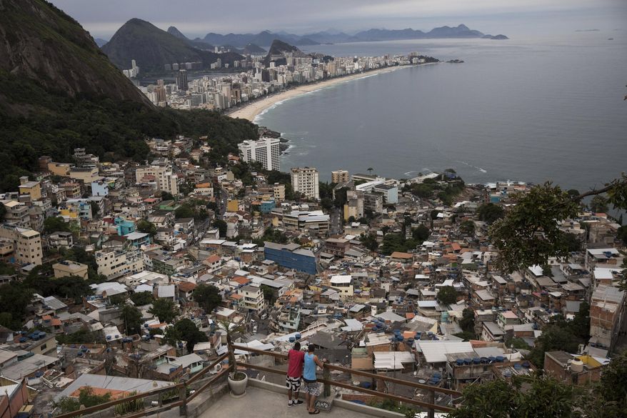 In this Oct. 29, 2017 photo, men overlook the city from the Vidigal slum, in Rio de Janeiro, Brazil. Opening the hillside favelas to tourists seemed like a winning idea: they get breathtaking views, the slum residents could cash in, and foreign visitors would see another part of the city, but soaring violence has rekindled a concern about safety. (AP Photo/Renata Brito)