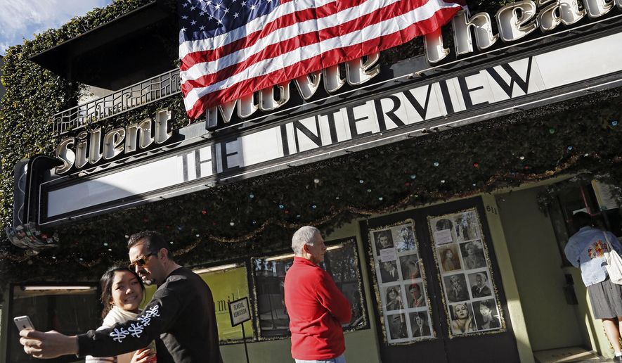 FILE - In this Dec. 25, 2014, file photo, a visitor takes a selfie with his friend in front of the Cinefamily at Silent Movie Theater in Los Angeles, prior to attending the movie "The Interview." The independent movie theater Cinefamily, which had numerous celebrity supporters, said Tuesday, Nov. 14, 2017, it is closing in the wake of investigations into the sexual misconduct of two of its executives. (AP Photo/Richard Vogel, File)