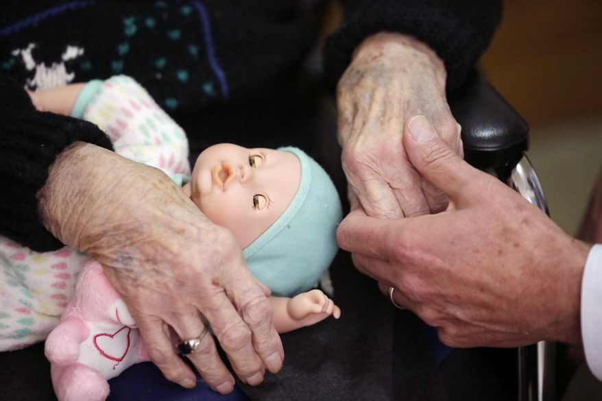 FILE - In this April 14, 2016, file photo, a son, at right, holds his mother's hand at her nursing home in Michigan. Many Americans have a blind spot when it comes to retirement planning: long-term care costs. Even though the majority of Americans will at some point need long-term care, few are planning for it. Many underestimate the costs and mistakenly believe health insurance can help cover it. (AP Photo/Carlos Osorio, File)