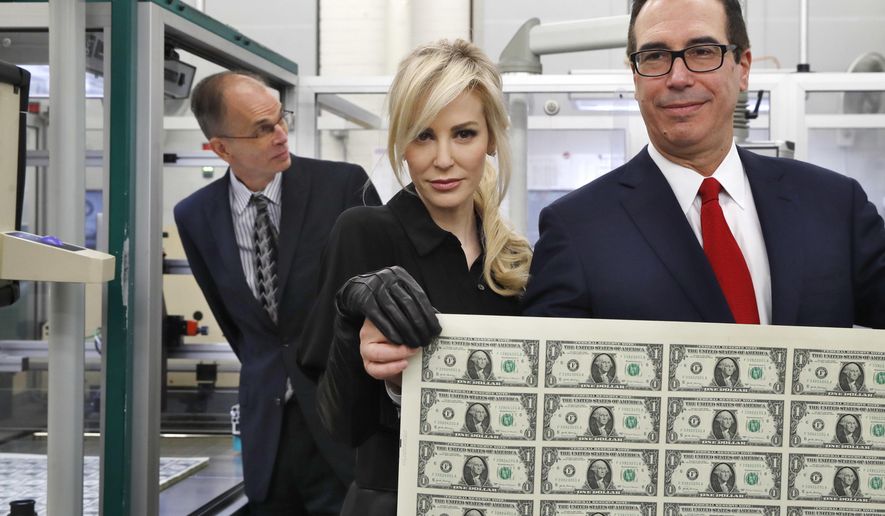 Treasury Secretary Steven Mnuchin, right, and his wife Louise Linton, hold up a sheet of new $1 bills, the first currency notes bearing his and U.S. Treasurer Jovita Carranza&#39;s signatures, Wednesday, Nov. 15, 2017, at the Bureau of Engraving and Printing (BEP) in Washington. The Mnuchin-Carranza notes, which are a new series of 2017, 50-subject $1 notes, will be sent to the Federal Reserve to issue into circulation. At left is BEP Director Leonard Olijar. (AP Photo/Jacquelyn Martin)