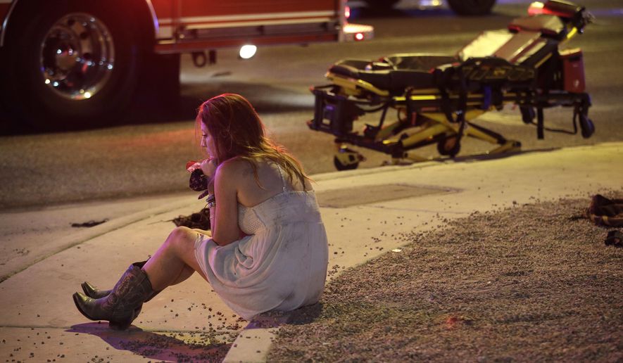 FILE - In this Oct. 2, 2017 file photo, a woman sits on a curb at the scene of a shooting outside of a music festival along the Las Vegas Strip, in Las Vegas. It came as little surprise to producers, but Showtime's documentary series this fall on mass shooting incidents was itself disrupted by mass shootings. The network cut back on reruns of the series following the Oct. 1 attack at a country music concert in Las Vegas that killed 58 people and injured hundreds. An episode that identified the 2016 Orlando nightclub shooting as the nation's most deadly event had to be changed because Las Vegas made that fact outdated.(AP Photo/John Locher, File)