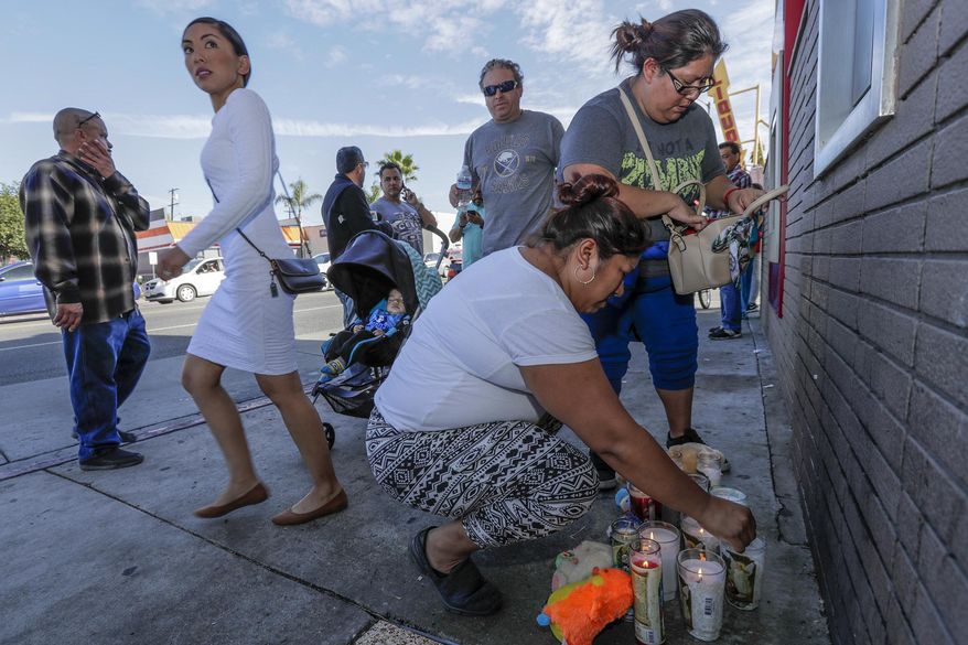 People gather at a makeshift memorial on the corner of Indiana Street and Whittier Blvd. in Boyle Heights, Friday, Nov. 17, 2017, where two boys were killed after they were struck by a Los Angeles County Sheriff's Department vehicle that was involved in a crash while responding to a radio call of shots fired. One of the boys died at the scene and the other at a hospital. Their mother was critically injured. (Irfan Khan/Los Angeles Times via AP)