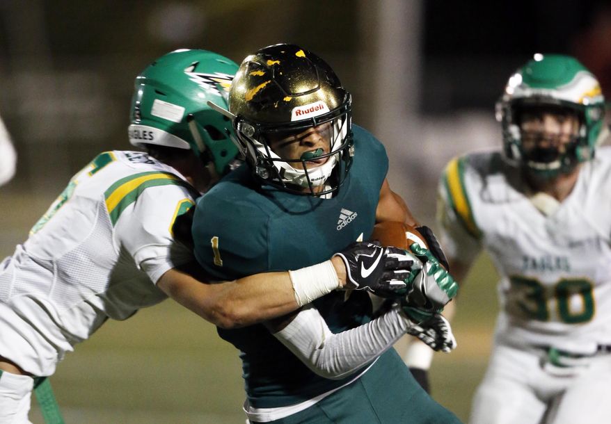 In the Sept. 28, 2017 photo, Knoxville Catholic's Dashon Bussell is hit by Rhea County's Reece Cooley, left, during a high school football game in Knoxville, Tenn. Bussell says he has not decided whether he plans to sign with his school in December or wait until February. The Western Michigan-bound receiver likes having the option. The high school senior has that choice thanks to a new set of NCAA recruiting rules that took effect this year. (Wade Payne/Knoxville News Sentinel via AP)