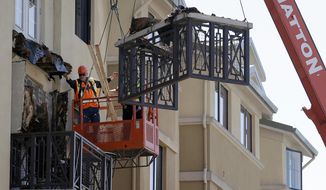 FILE - In this June 16, 2015 file photo, workers remove part of a balcony that collapsed at the Library Gardens apartment complex in Berkeley, Calif. Relatives of six college students who died when the balcony collapsed, have reached a settlement with the owners of the apartment building and the company that managed it. (AP Photo/Jeff Chiu, File)