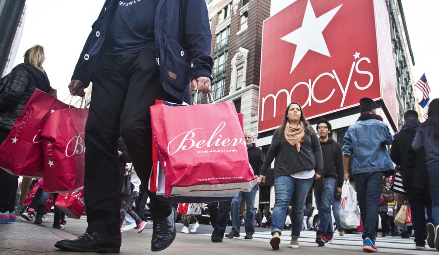 FILE - In this Nov. 27, 2015, file photo, shoppers carry bags as they cross a pedestrian walkway near Macy's in Herald Square, in New York. At Macy's flagship store in New York, a chance to sit on Santa Claus' lap is by appointment only in 2017, for the first time ever. (AP Photo/Bebeto Matthews, File)
