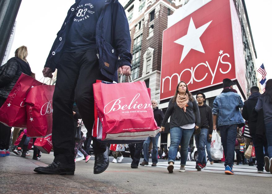 FILE - In this Nov. 27, 2015, file photo, shoppers carry bags as they cross a pedestrian walkway near Macy's in Herald Square, in New York. At Macy's flagship store in New York, a chance to sit on Santa Claus' lap is by appointment only in 2017, for the first time ever. (AP Photo/Bebeto Matthews, File)