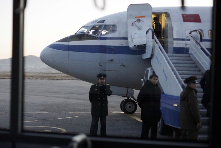FILE - In this file photo taken Monday, Dec. 19, 2011, North Korean officials wait for passengers to board an Air China flight at Pyongyang airport in Pyongyang, North Korea. State-owned airline Air China suspended flights Tuesday between Beijing and North Korea due to a lack of demand, deepening the North's isolation amid mounting U.N. sanctions over its nuclear and missile programs.(AP Photo/ Greg Baker, File)