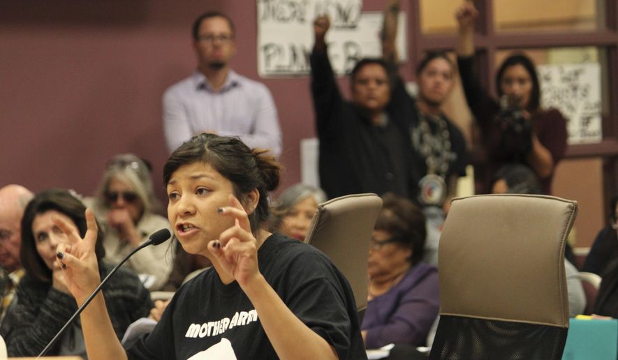 Ahjani Yepa, a Jemez Pueblo member, testifies in opposition of a proposed ordinance that would govern oil and gas development in Sandoval County as others raise their fists in solidarity during a County Commission meeting in Bernalillo, N.M., on Thursday, Nov. 16, 2017. Critics of the ordinance say it does not go far enough to protect groundwater resources. (AP Photo/Susan Montoya Bryan)