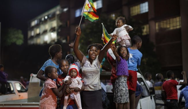Zimbabweans celebrate at night at an intersection in downtown Harare, Zimbabwe Tuesday, Nov. 21, 2017. Mugabe resigned as president with immediate effect Tuesday after 37 years in power, shortly after parliament began impeachment proceedings against him. (AP Photo/Ben Curtis)