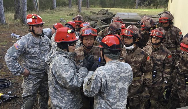In this Saturday, Nov. 18, 2017 photo, soldiers from the U.S. Army and China&#x27;s People&#x27;s Liberation Army carry out a joint rescue response to a natural disaster in an exercise at Camp Rilea Armed Forces Training Center near Warrenton, Ore. It was only a drill, but roughly 100 soldiers from China and the U.S. and their top commanders are ready to use what they learned in a real disaster. The commander of U.S. Army-Pacific said Sunday - the last day of the exercise - that carrying out joint disaster responses shouldn’t depend on the state of relations between the two world powers. Gen. Robert Brown says the participants found a common interest in saving lives. (AP Photo/Andrew Selsky)