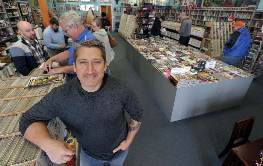 In this Wednesday, Nov. 8, 2017, photo, John Dudas, owner of Carol and John's Comic Book Shop, poses during New Comic Day in Cleveland. Some smaller retailers will tug at shoppers’ heartstrings during the holidays, trying to create an emotional experience or connection that a big national chain might not provide. Dudas recently participated in Local Comic Shop Day, which he calls the comic book industry’s equivalent of Black Friday. People lined up outside his store for limited-edition comics, and had a great time while they waited. (AP Photo/Tony Dejak)