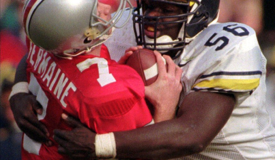 FILE - In this Nov. 23, 1996, file photo, Ohio State quarterback Joe Germaine, left, is sacked by Michigan defender James Hall, ending a drive during the third quarter of an NCAA college football game in Michigan's 13-9 upset victory over No. 2 Ohio State at Ohio Stadium in Columbus, Ohio. (AP Photo/Charles Rex Arbogast, File)