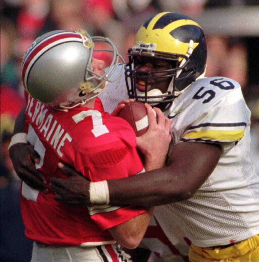 FILE - In this Nov. 23, 1996, file photo, Ohio State quarterback Joe Germaine, left, is sacked by Michigan defender James Hall, ending a drive during the third quarter of an NCAA college football game in Michigan's 13-9 upset victory over No. 2 Ohio State at Ohio Stadium in Columbus, Ohio. (AP Photo/Charles Rex Arbogast, File)