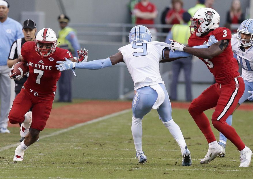 North Carolina cornerback K.J. Sails (9) is blocked by North Carolina State's Germaine Pratt (3) as North Carolina State running back Nyheim Hines (7) runs the ball during the first half of an NCAA college football game in Raleigh, N.C., Saturday, Nov. 25, 2017. (AP Photo/Gerry Broome)