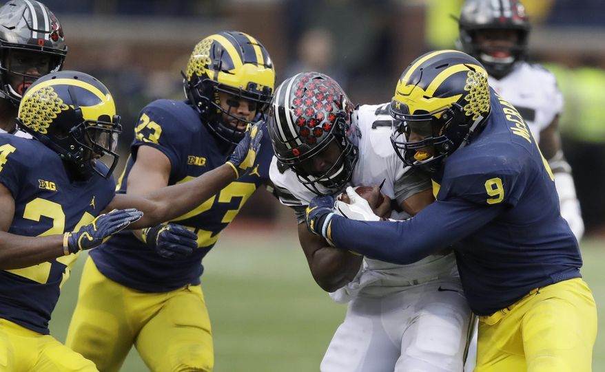 Ohio State quarterback J.T. Barrett (16) is stopped by Michigan linebacker Mike McCray (9) during the first half of an NCAA college football game, Saturday, Nov. 25, 2017, in Ann Arbor, Mich. (AP Photo/Carlos Osorio)