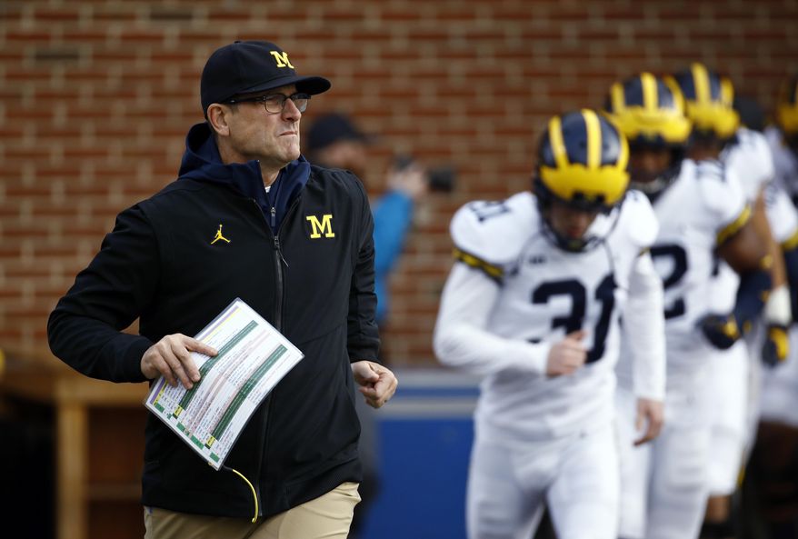 FILE - In this Nov. 11, 2017, file photo, Michigan coach Jim Harbaugh runs onto the field with his team before an NCAA college football game against Maryland in College Park, Md. Harbaugh is winless against Ohio State in the three rivalry games since he became coach. (AP Photo/Patrick Semansky, File)