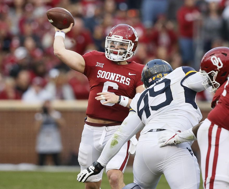 Oklahoma quarterback Baker Mayfield (6) passes under pressure from West Virginia West Virginia defensive lineman Lamonte McDougle (49) in the second quarter of an NCAA college football game in Norman, Okla., Saturday, Nov. 25, 2017. (AP Photo/Sue Ogrocki)