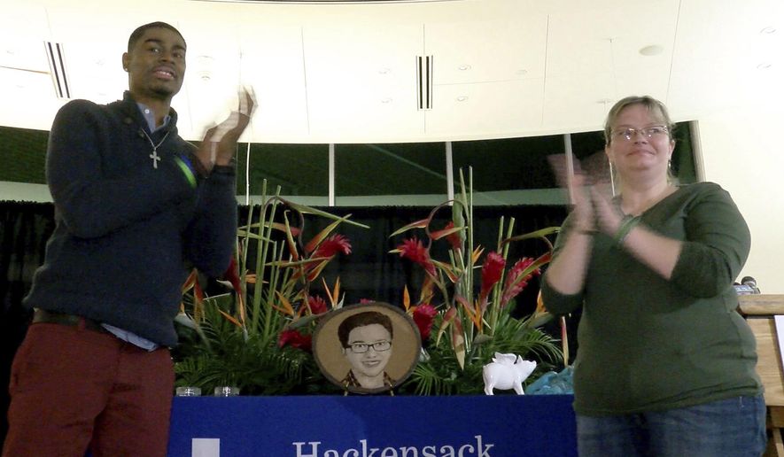 In this Nov. 15, 2017, photo, Andre Thomas and Missy Masse clap after unveiling the floragraph of Luke Bautista during a ceremony at Jersey Shore University Medical Center in Neptune, N.J. After Luke's death at age 15, his organ donation saved helped save their lives. (Thomas P. Costello/The Asbury Park Press via AP)