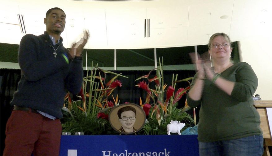 In this Nov. 15, 2017, photo, Andre Thomas and Missy Masse clap after unveiling the floragraph of Luke Bautista during a ceremony at Jersey Shore University Medical Center in Neptune, N.J. After Luke's death at age 15, his organ donation saved helped save their lives. (Thomas P. Costello/The Asbury Park Press via AP)