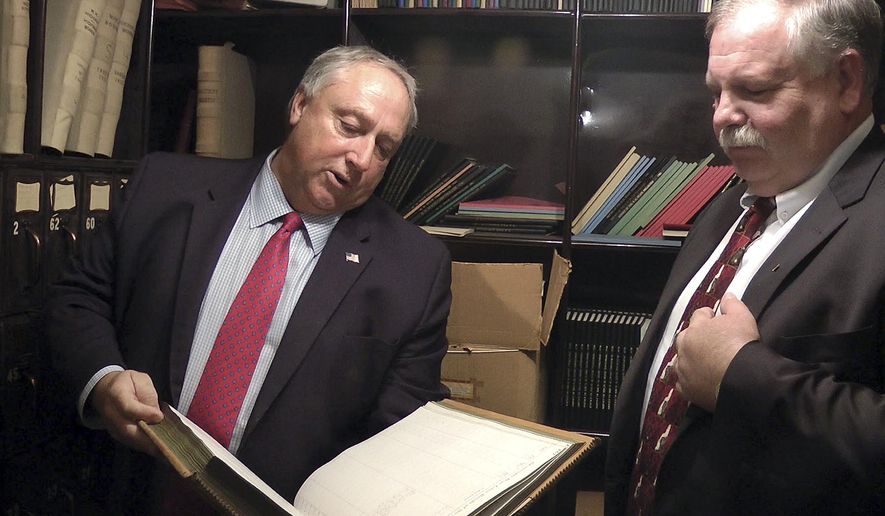 Terry Pfaff, left, chief of staff, New Hampshire House of Representatives, inspects a book found in a vault at the Statehouse, Monday, Nov. 27, 2017, in Concord, N.H. Beside him is House Speaker Shawn Jasper, right. The vault, which had been locked for decades in a room that once served as the state treasury in the 1800s, is now assigned to the Senate Finance Committee. (AP Photo/Holly Ramer)