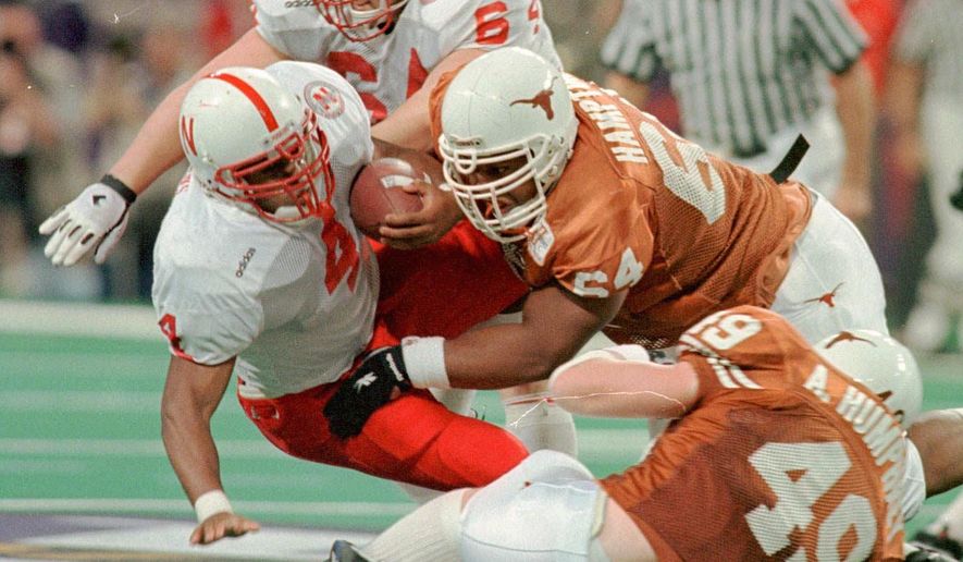 In this Dec. 7, 1996, photo, Texas' Casey Hampton, top right, and Aaron Humphrey, bottom right, combine to stop Nebraska's DeAngelo Evans at the line of scrimmage in the Big 12 Championship NCAA college football game in St. Louis. (Ralph Barrera/Austin American-Statesman via AP)