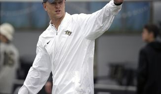 FILE - In this Nov. 24, 2017, file photo, Central Florida head coach Scott Frost waves to fans as he takes the field before an NCAA college football game against South Florida, in Orlando, Fla. Nebraska fans are gearing up for what to them seems to be the imminent arrival of native son Scott Frost as the Cornhuskers’ new football coach.  T-shirts imploring Frost to “Make Nebraska Great Again” are popular, bars around town are setting drinks on “Hire Scott Frost Now!” coasters, and Facebook pages in support of Frost have popped up. Frost, whose Central Florida Golden Knights are unbeaten and hosting Memphis in the American Athletic Conference championship game this week, has been the topic du jour every day for a month on the all-sports radio stations in Omaha and Lincoln. (AP Photo/John Raoux, File)