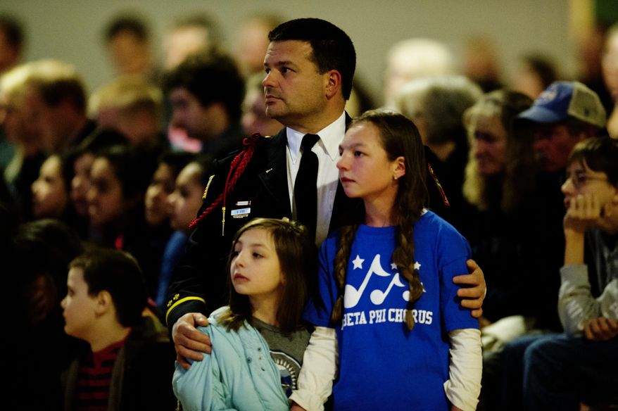 Gatlinburg firefighter Steve Ebb holds his daughters Breanna, 8, left, and Alyssa, 12, during a memorial service held at at Rocky Top Sports World marking the first anniversary of the Gatlinburg wildfire in Gatlinburg, Tenn., Tuesday, Nov. 28, 2017. The wildfires roared through Gatlinburg last November, killing 14 people in the area and damaging or destroying over 2,000 buildings. (Calvin Mattheis/Knoxville News Sentinel via AP)