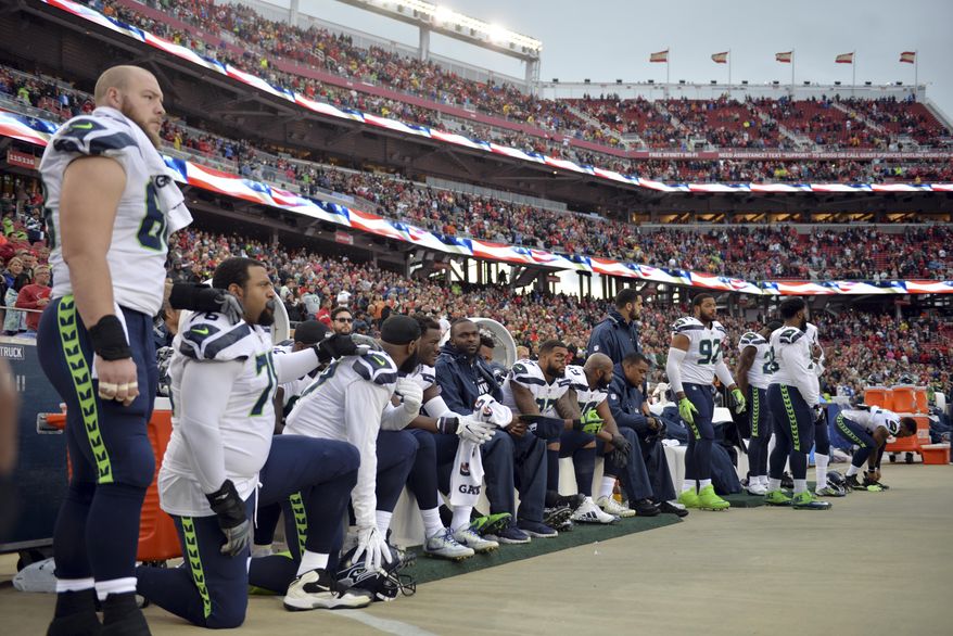 FILE - In this Nov. 26, 2017, file photo, Seattle Seahawks players sit and kneel during the playing of the national anthem before an NFL football game against the San Francisco 49ers, in Santa Clara, Calif. President Donald Trump is renewing his complaints about NFL players who kneel during the national anthem. Players have been kneeling to protest racism and police brutality, particularly toward people of color. Trump says the act is disrespectful and is hurting the game.(AP Photo/Don Feria, File)