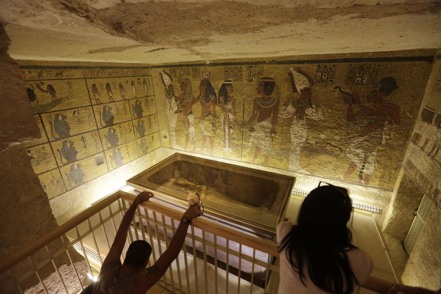 FILE - In this Thursday, Nov. 5, 2015, file photo, tourists look at the tomb of King Tut as it is displayed in a glass case at the Valley of the Kings in Luxor. Artifacts from the tomb will go on display at the California Science Center in Los Angeles in January 2018 to kick off a ten-city tour to mark the upcoming 100th anniversary of the tomb's discovery. King Tut’s tomb was discovered in 1922, more than 3000 years after his death. (AP Photo/Amr Nabil, File)