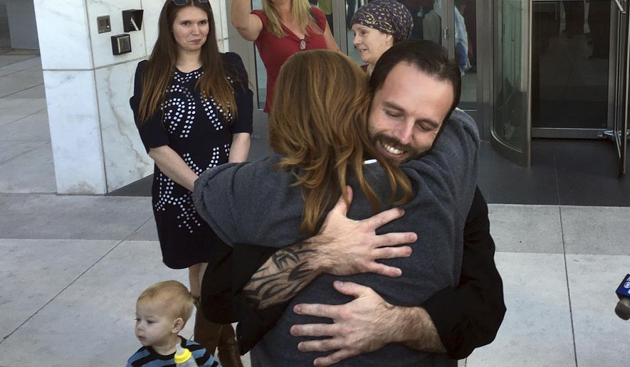 Nevada ranching standoff defendant Ryan Payne, facing camera, hugs a friend outside the U.S. District Courthouse in Las Vegas following his release on Friday, Dec. 1, 2017, after 22 months in federal custody. Payne, 34, of Anaconda, Mont., was arrested in 2016 in Oregon following an occupation of a federal wildlife refuge. He is standing trial with Nevada rancher Cliven Bundy and two Bundy sons in a 2014 armed confrontation with federal agents. (AP Photo/Ken Ritter)