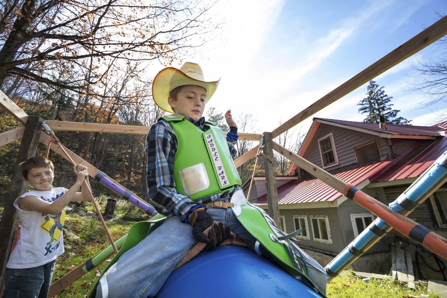 In this Oct. 28, 2017 photo, Shawn Rake, 11, trains on his practice rig with the help of his younger brother, Jason, 9, in Equinunk, Pa. Most 11-year-olds ride bikes. Shawn Rake rides bulls. Competing under the BLM Bull and Rodeo Co. in Virginia, the Equinunk boy started riding miniature bulls in the summer. Although the animals are called miniature, they can weigh more than 800 pounds.(Frank Wilkes Lesnefsky/The Times & Tribune via AP)